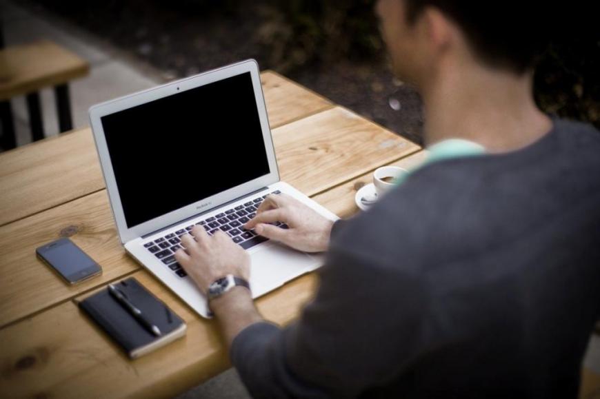 Mann arbeitet mit seinem Notebook im Freien.